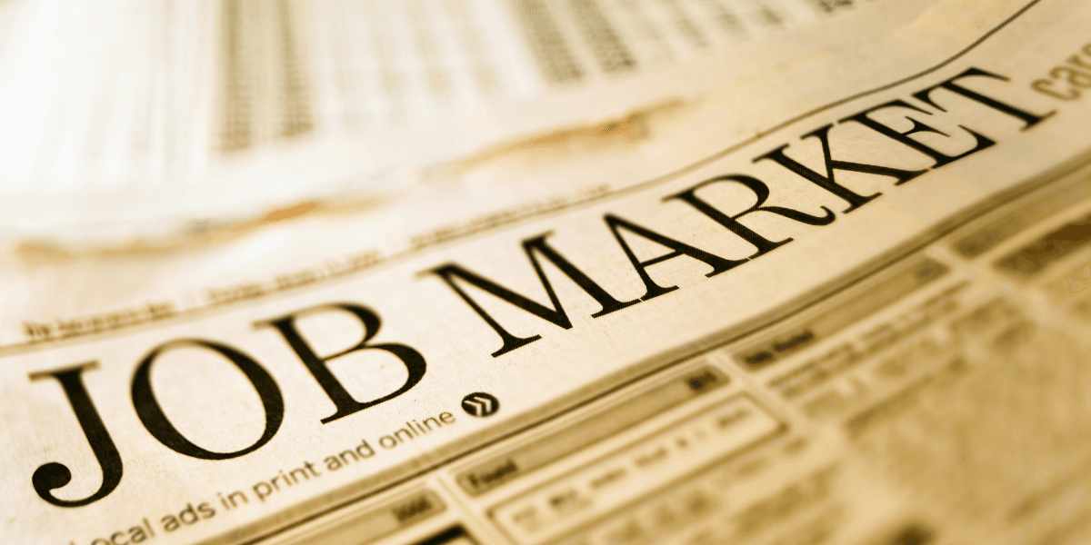Close-up of a newspaper headline reading "JOB MARKET" with job listings below