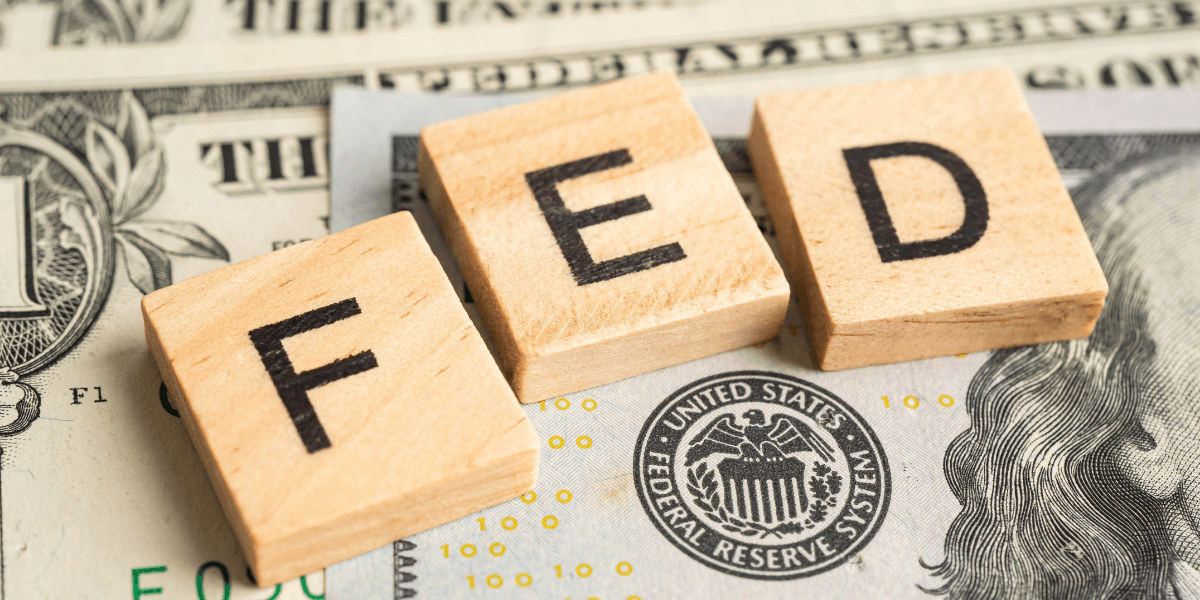 Wooden blocks spelling "FED" on a background of U.S. dollar bills