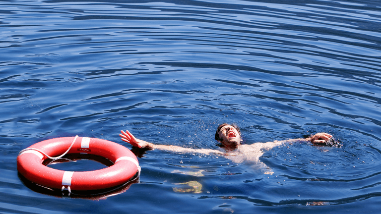 Person swimming near a red life ring in open water.