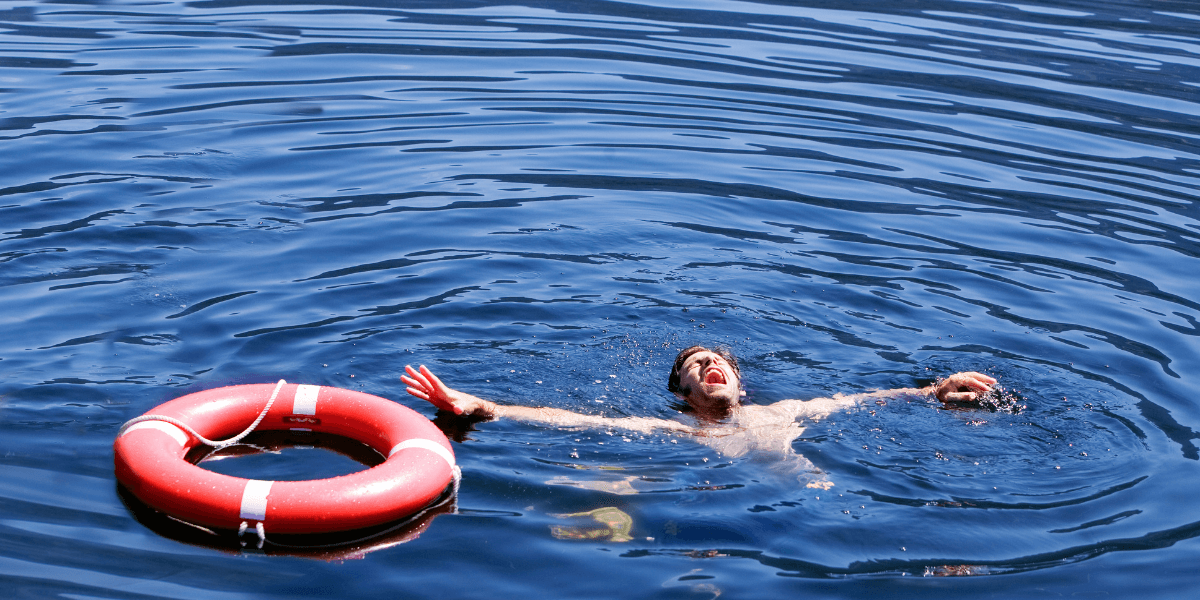 Person swimming near a red life ring in open water.