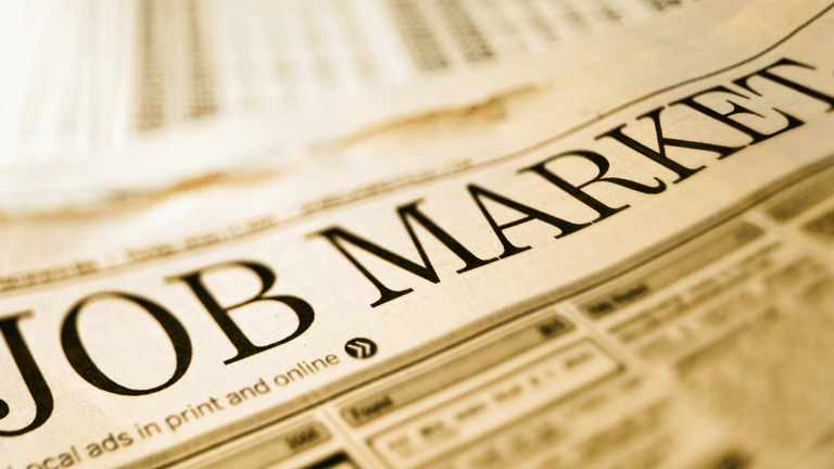 Close-up of a newspaper headline reading "JOB MARKET" with job listings below