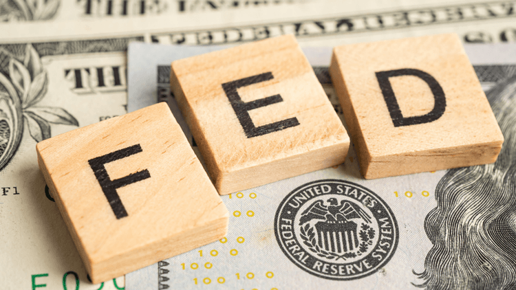 Wooden blocks spelling "FED" on a background of U.S. dollar bills