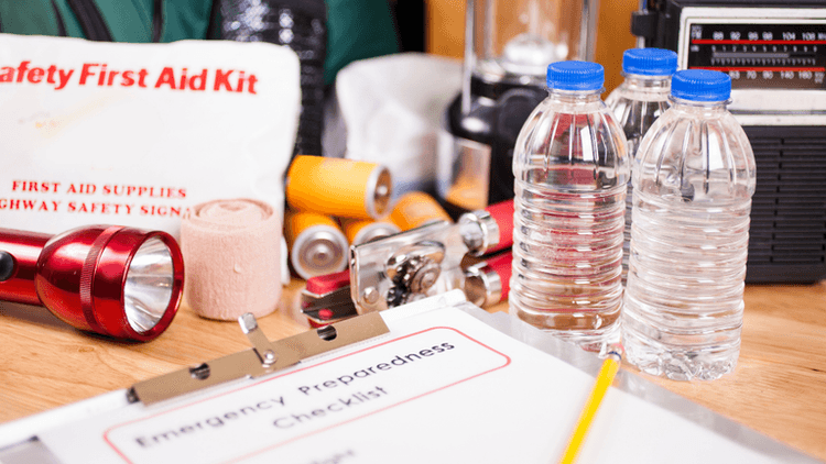 Emergency preparedness supplies including a first aid kit, water bottles, flashlight, and checklist