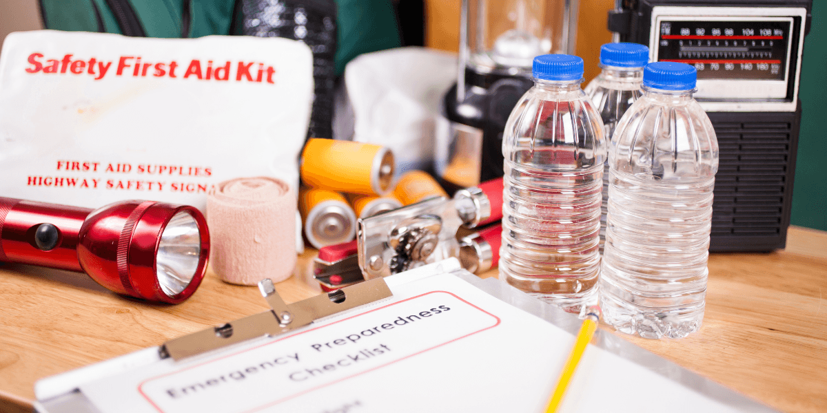 Emergency preparedness supplies including a first aid kit, water bottles, flashlight, and checklist